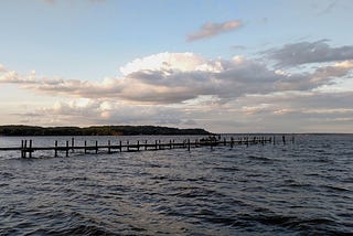 A scene of the waterfront with a dock during the evening.