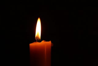 A single candle flame against a dark background