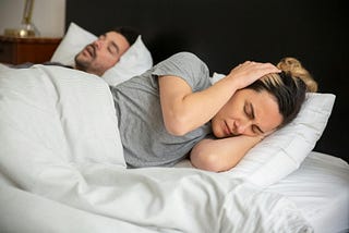 man snoring, woman covering her ears