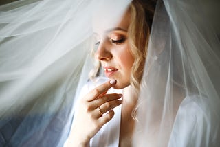 Bride covered with veil contemplates.