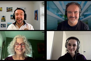 Photo Alt text: A video call screenshot features four participants: Neil, a smiling man with headphones and a white shirt, against colorful artwork; Antonio, a bearded man with glasses and headphones, smiling in front of a modern building virtual background; Debra, a woman with curly gray hair and red glasses, smiling in a room with green walls and windows; and Laura, a younger woman with glasses, headphones, a dark hoodie, smiling in a bright room with a thermostat on the wall.