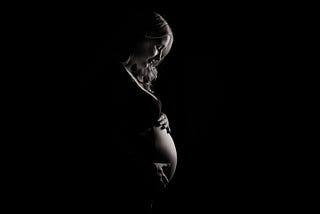 Black and white photo of a pregnant person holding their stomach