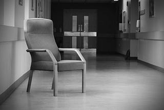 Black & White Picture of a Hospital corridor with a chair in the foreground