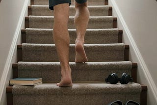 A man walking up stairs ignoring the things he’s supposed to be taking up with him.