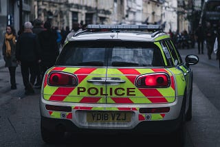 Picture of the back of a police car on a busy city street