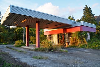 Abandoned gas station overgrown with weeds
