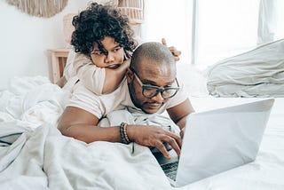 Father working from home with his child on his back