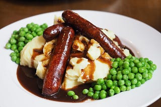 Sausage and mashed potatoes with peas.