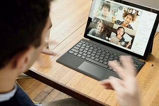 Person at desk in meeting with other people through a video conferencing app