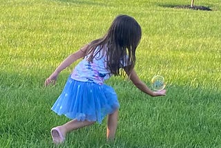 Young girl with hand reaching out, palm facing up. A large bubble is right above her palm.