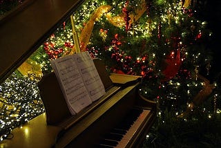 Piano and sheet music next to a Christmas tree