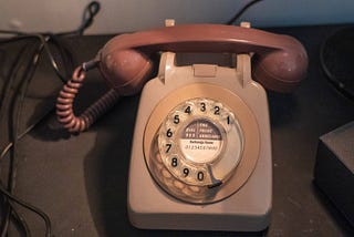 A beige, old model rotary telephone.