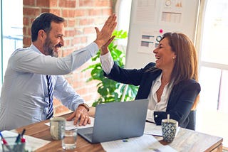 Colleagues high-fiving at work