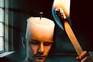 Photo prompt. A human, candle. Candles wax and wick take the place of a forehead, and top of head completely, of a man, or woman. A hand is extended outwards, for point of view, and is holding a matchstick. Matchstick is lit up, and on fire. Matchstick on fire. Looks as if they are lighting their own wick, which is their head.