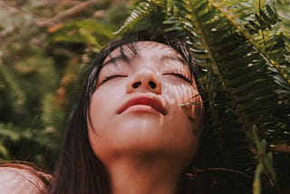 close up of a girl and her eyes closed embracing mother nature around her