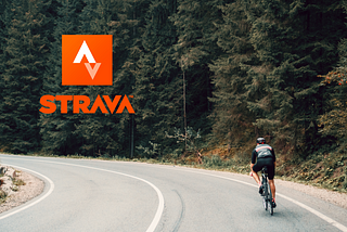 Biker riding down a road, Strava logo on the back.