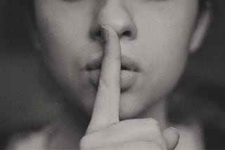 Woman with finger to mouth to say shhhhhh in black and white