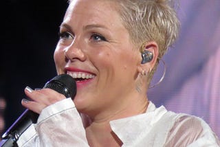 Close up shot of the musician Pink, performing with a microphone and short, blonde hair.