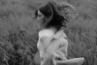 Grayscale Photo of a Woman Running in a Field