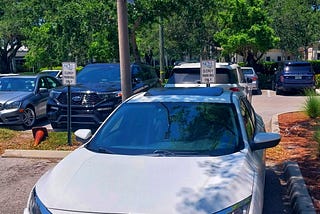 a honda parked in a spot reserved for clergy only at a hospital emergency room entrance.