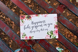 A card with a quote on happiness placed on a wooden bench