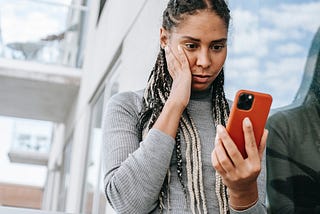 Concerned black woman using smartphone on street