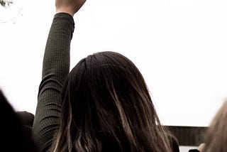 Woman rising her fist towards the grey sky