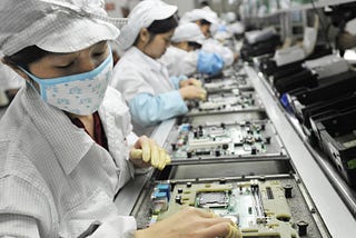 A bunch of poor women assemble iPhones on a factory line while wearing face masks, but it won’t stop the from getting leukemia like many of their colleagues.