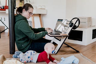 Woman working on laptop while watching her baby