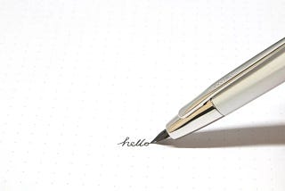 The tip of a beautiful fountain pen writing the word “hello” (Real Insight)