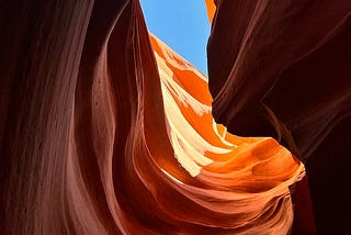 the blue sky shows above the vaginal opening of a gently folding cave structure