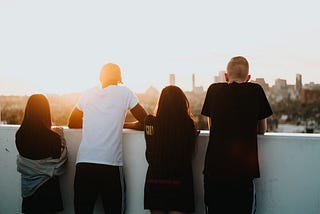 Group of young people overlooking a city from the top of a building