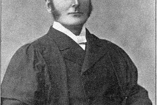 A black and white photograph of a the rector of Exeter College in academic regalia, 1883