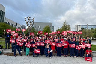 Photo of a large group of several dozen nurses standing together, most holding signs reading, “New Orleans RN: READY TO FIGHT!”