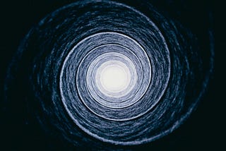 Abstract circular light pattern converging toward a bright centre, symbolising reinforcing loops and intentional direction.