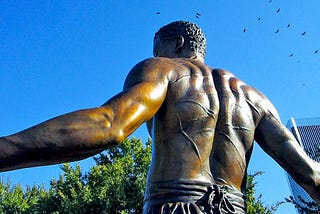 Bronze statue of an African-American man, shirtless with whip scars on his back