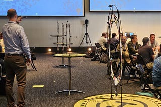 A group of people in a room with a projector are calibrating their drones to navigate targets.
