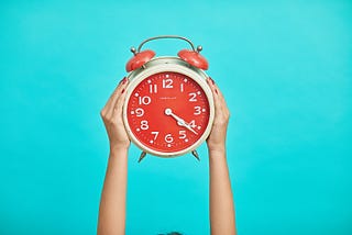 Colorful photo of a red alarm clock on a bright blue background