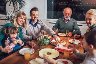 Extended family with parents, grandparents and children share a meal at a table.