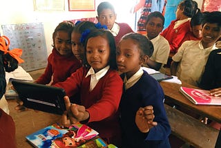 Students gather around a tablet to learn.