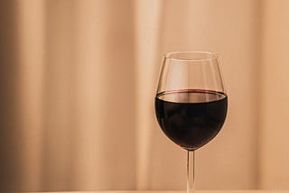 A glass of dark red wine on a table.
