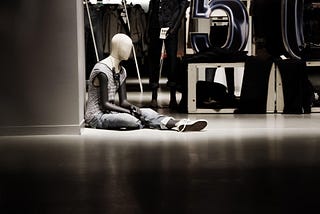 A store display mannequin sitting down, abandoned, to illustrate our sense of being controlled and abandoned by the world.