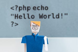 A code snippet saying “Hello world” with a paper doll of a programmer in front of it