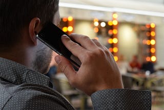 A man in his business office talking to a client on his cell phone. Using relationship marketing to bond with his clients.