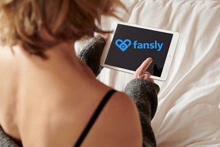 girl looking at her tablet with the Fansly logo on it