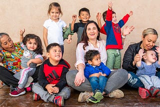 Child care provider Miren Algorri surrounded by children and her co-workers.