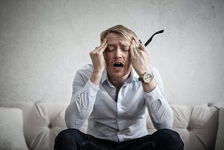 Man rubbing his head in work exhaustion