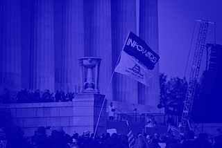 A flag featuring the “InfoWars” logo flies over a crowd of protesters in front of columns at the Lincoln Memorial in Washington, D.C.