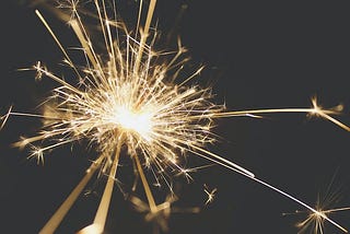 Image of a sparkler flaring against a dark background.
