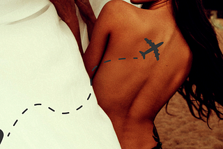 the bare back of a beautiful woman changing with an airplane tattoo and flight path on her back